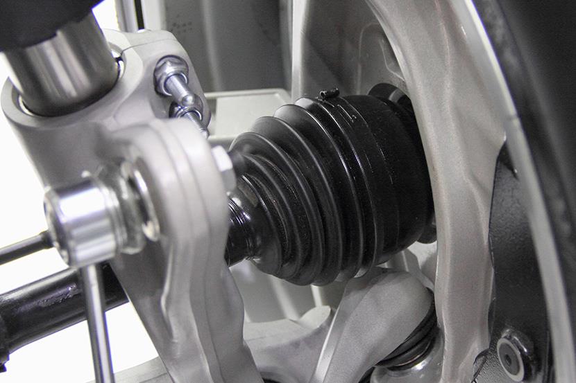 closeup of a cars driveshaft tripod cv joint shock absorber stabilizer lever disk and tire